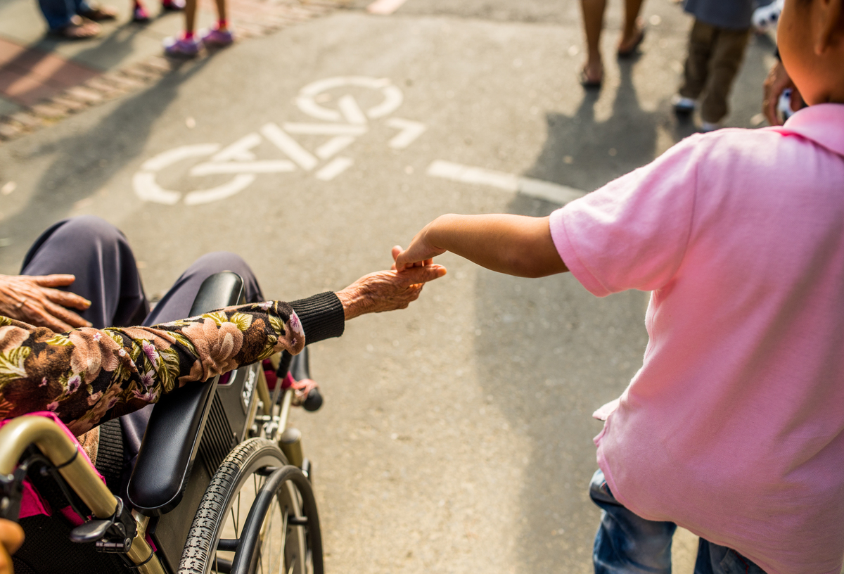 A child holds hands with a person in a wheelchair