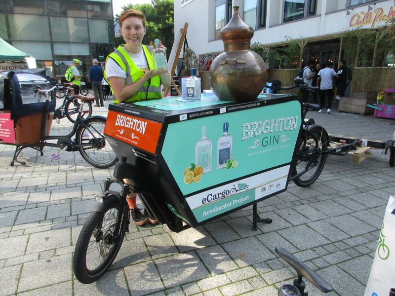 A stationary electric cargo bike being used as a stand to sell local Brighton Gin