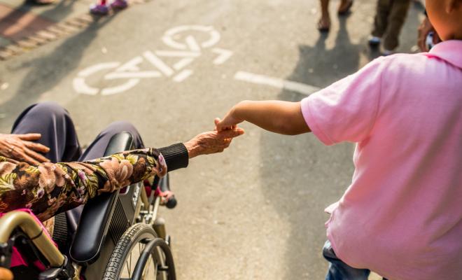A child holds hands with a person in a wheelchair